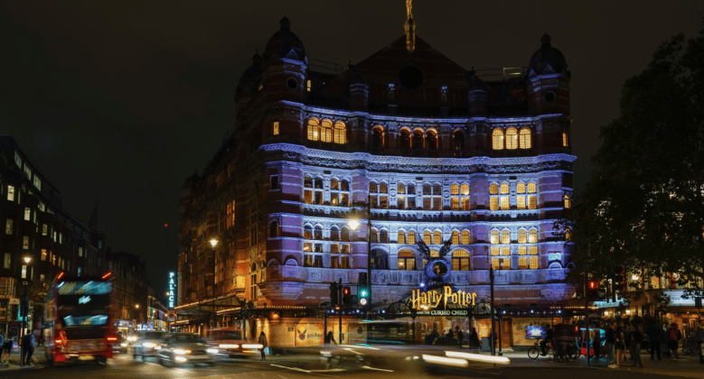 Outside photo of the Palace Theatre in London at night. The theatre is lit up with a blue-white light.